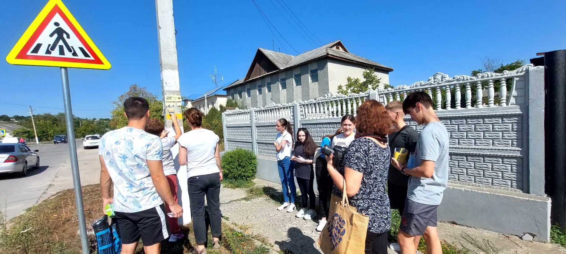 Skupina lidí na ulici přihlíží vytváření turistické značky na sloup